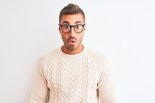 Young handsome man wearing glasses and winter sweater over isolated background scared in shock with a surprise face, afraid and excited with fear expression