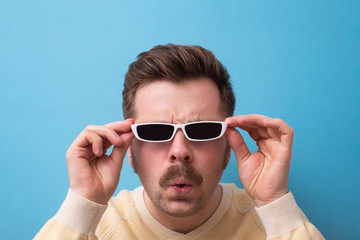 caucasian man with funny mustache sunglasses looking at camera surprised.