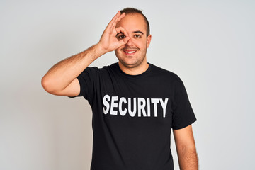 Obraz premium Young safeguard man wearing security uniform standing over isolated white background with happy face smiling doing ok sign with hand on eye looking through fingers