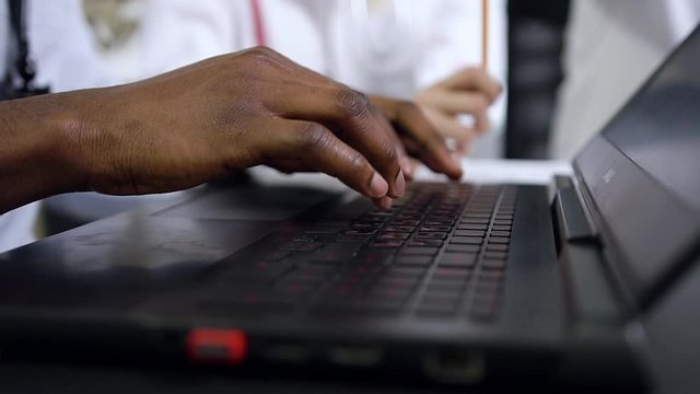 Slow motion of well-maintained dark-skinned male hands which typing on the computer keyboard