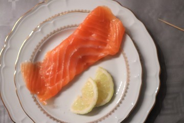 Tranche de saumon fumé et tranches de citron sur une assiette blanche