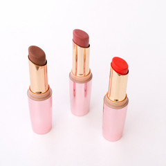 Brown and red lipsticks with pink cap on white background.