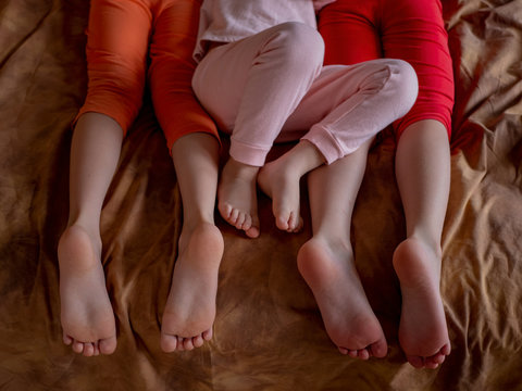 Three brother boys were lying on couch and were busy with phone and tablet. boys are wearing barefoot home pajamas. Feet and toes closeup. Tender baby feet