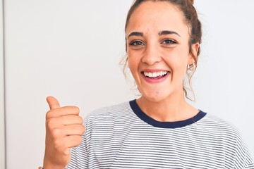 Young redhead modern woman wearing a bun over isolated background pointing and showing with thumb up to the side with happy face smiling