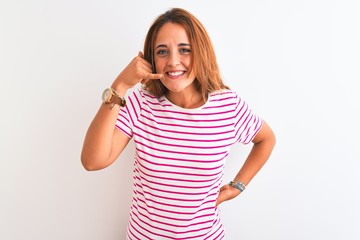 Young redhead woman wearing striped casual t-shirt stading over white isolated background smiling doing phone gesture with hand and fingers like talking on the telephone. Communicating concepts.