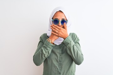 Young Arab woman wearing hijab and summer sunglasses over isolated background shocked covering mouth with hands for mistake. Secret concept.