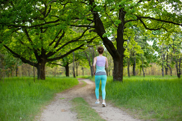 Fototapeta na wymiar A young sports girl running in a quit green summer forest. Sport and wellness