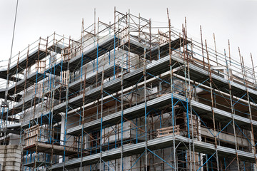 Fototapeta premium Building under construction in scaffolding. Construction site background. Europe, Italy.