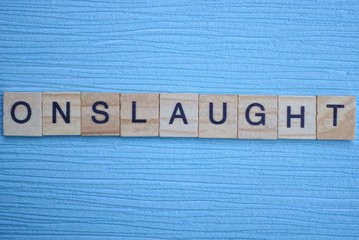 gray word onslaught from small wooden letters on a blue table