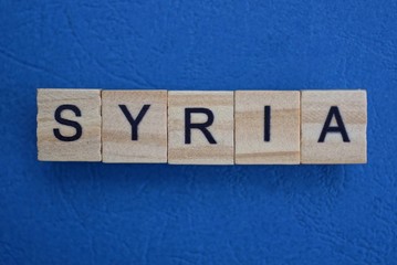 gray word syria from small wooden letters on a blue table