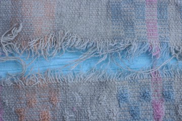 piece of old gray fabric with a torn big hole on a blue background