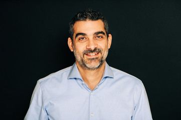 Studio portrait of handsome man wearing formal blue shirt, posing on black background