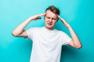 Naklejka premium Portrait of young teen man having awful headache while standing over green background.