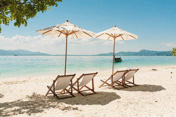 Wooden empty chairs and umbrella on luxury resort beach hotel. Relax on the beach, sea and blue...