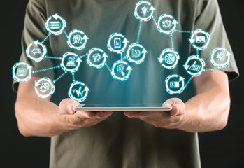Young man with tablet PC on dark background, closeup