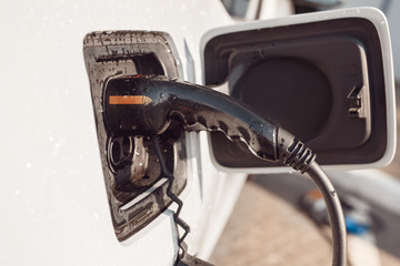 Tramsportation. Elcetric car close-up at charging station no people charging with ev charger in...