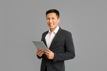 Portrait of Asian businessman with tablet computer on grey background