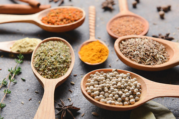 Spoons with different spices on dark background