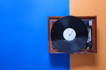 Record player with vinyl disc on color background