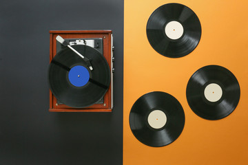 Record player with vinyl discs on color background