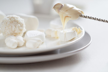 Various white candies, marshmallows and peanut butter on a light background