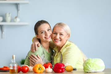 Mature woman and her adult daughter together in kitchen