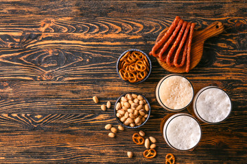Glasses of different tasty beer with snacks on wooden table