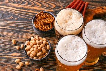 Glasses of different tasty beer with snacks on wooden table