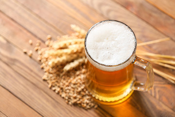 Mug of tasty beer on wooden background