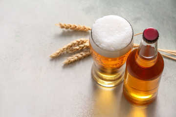 Bottle and glass of tasty beer on light background