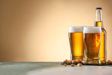 Bottle and glasses of tasty beer on light background