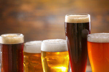 Glasses of different tasty beer on blurred background