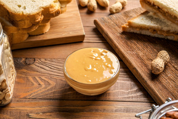 Bowl with tasty peanut butter on wooden table