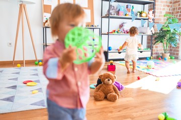 Adorable toddlers playing around lots of toys at kindergarten