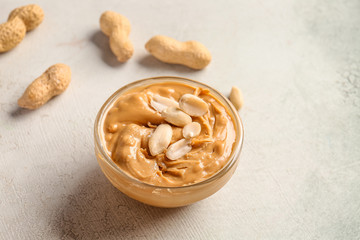 Tasty peanut butter in bowl on light background