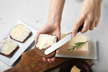 Woman spreading fresh butter onto slice of bread