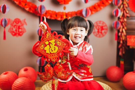 Chinese baby girl traditional dressing up hold a Fu means 'lucky' greeting sign