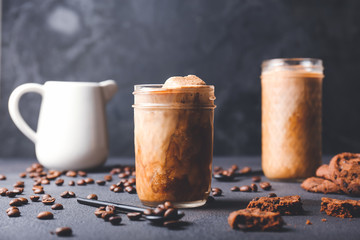 Glass of tasty iced coffee and cookies on dark background