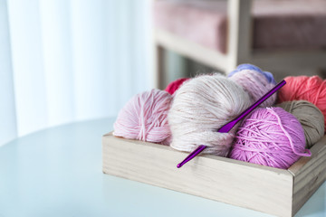 Box with knitting yarn on table at home