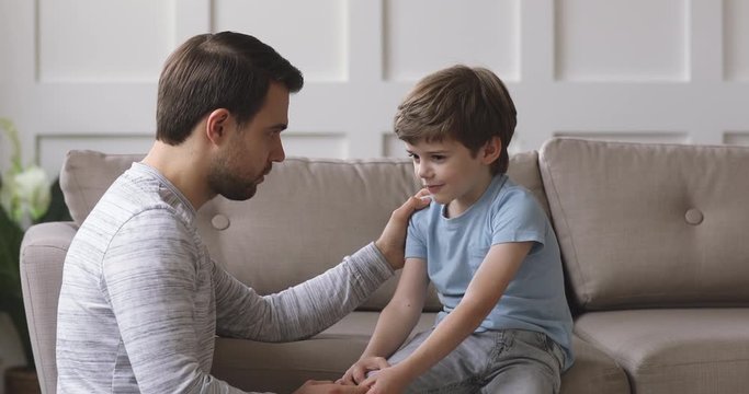 Caring single father comforting talking with kid son at home
