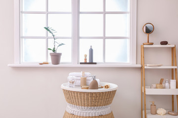 Body care cosmetics with accessories on table and rack in bathroom