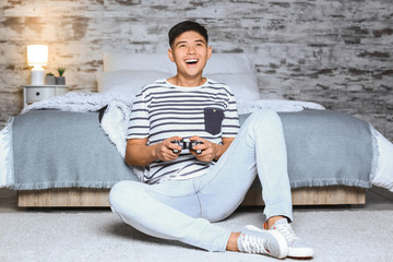 Asian man playing video game at home in evening