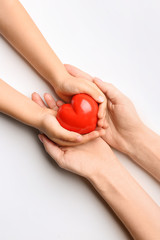 Hands of child and adult with red heart on white background. Cardiology concept
