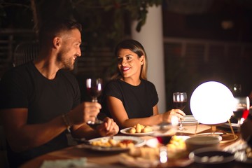 Young beautiful couple dinning on celebration toasting and smiling at terrace