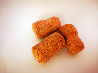 Three wine corks lie on a white background