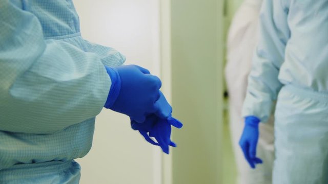 employee puts on blue rubber gloves in plant workshop locker