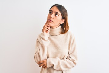 Beautiful redhead woman wearing winter turtleneck sweater over isolated background with hand on chin thinking about question, pensive expression. Smiling with thoughtful face. Doubt concept.