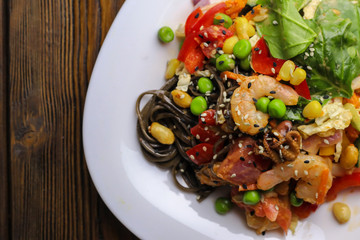 Tasty soba pasta with seafood and vegetables on wooden table