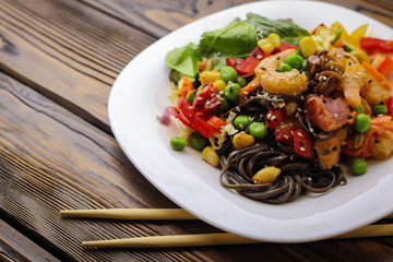 Tasty soba pasta with seafood and vegetables on wooden table
