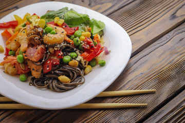 Tasty soba pasta with seafood and vegetables on wooden table